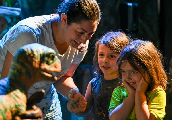 Anna Hodgekiss interacts with a baby Velociraptor along with her children Loki (left) and Thor at “Jurassic World: The Experience” Wednesday, June 7, 2023 at the Pullman Yards in Atlanta. (Daniel Varnado/ For the AJC)