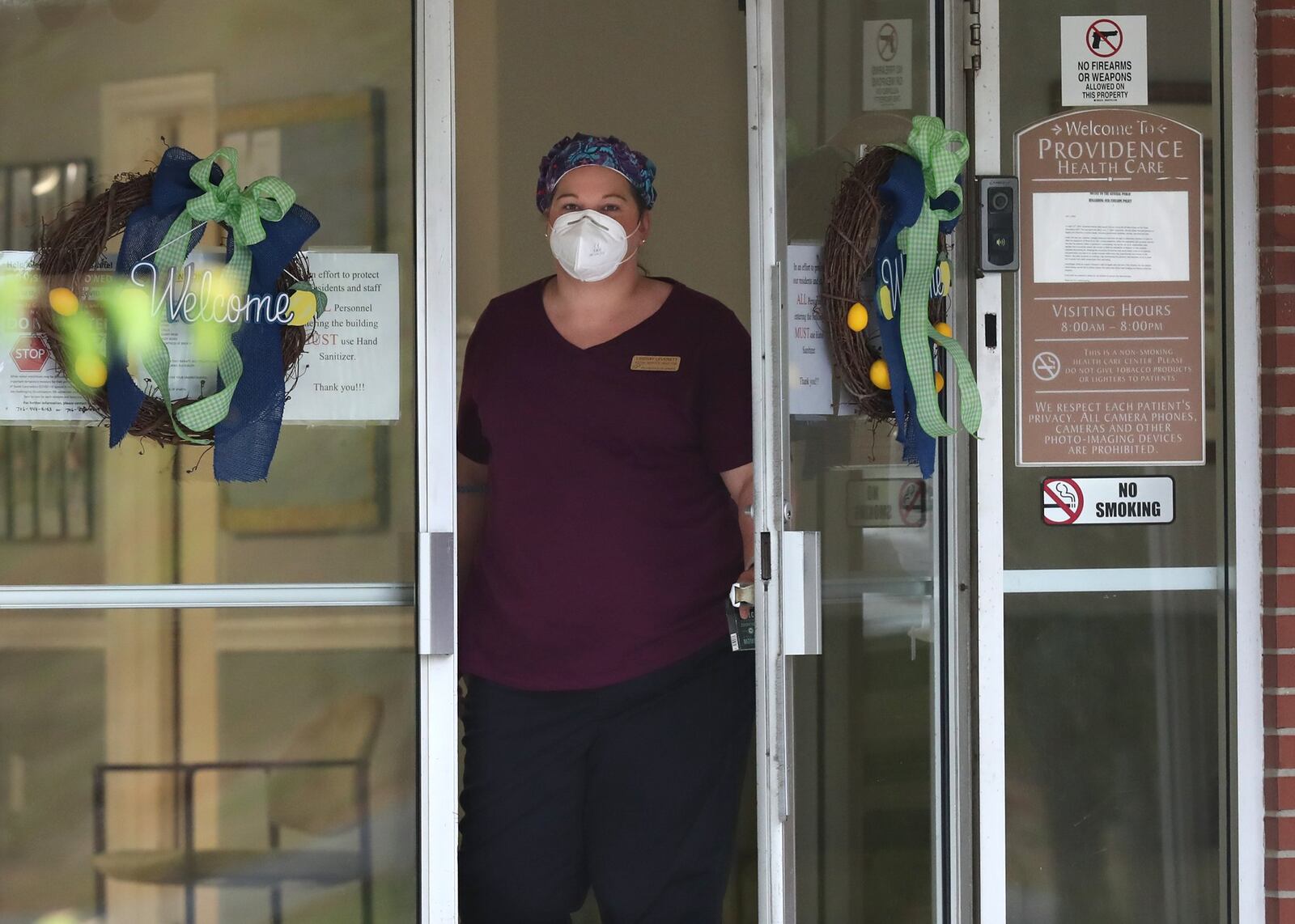 A healthcare worker on Wednesday looks out the main doors at Providence of Sparta Health and Rehabilitation, where at least 38 patients and 11 staff members have been infected with coronavirus. The nursing home has reported one coronavirus death. Hancock County, halfway between Augusta and Macon, has become a new coronavirus hot spot in Georgia. Two-thirds of the Hancock cases are in the county’s two nursing homes. (PHOTO by Curtis Compton ccompton@ajc.com)