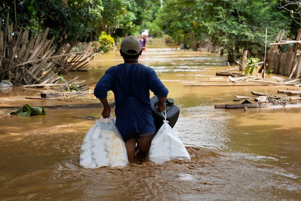 FILE - Local residents carrying food wade through a flooded road in Naypyitaw, Myanmar, Saturday, Sept. 14, 2024. (AP Photo/Aung Shine Oo, File)