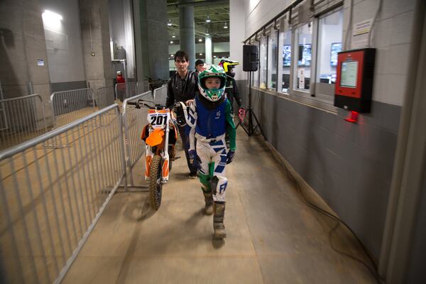 Bob McGee and his son Ryder, 7, head to the starting line during the Supercross Amateur racing event in the Mercedes-Benz Stadium on Sunday, March 4, 2018. McGee said his son has been racing since he was 4 years old.  STEVE SCHAEFER / SPECIAL TO THE AJC