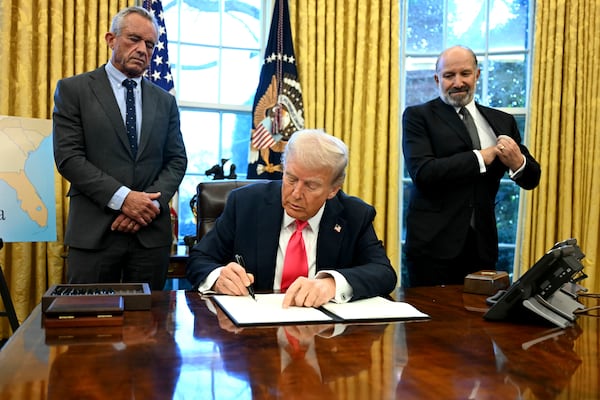 President Donald Trump signs an executive order as Health and Human Services Secretary Robert F. Kennedy Jr., left, and Commerce Secretary Howard Lutnick watch in the Oval Office at the White House in Washington, Thursday, Feb. 25, 2025. (Pool via AP)