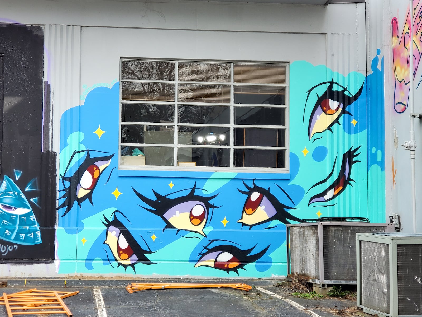 Drew Borders’ mural features anime-inspired eyes against a blue and green background.