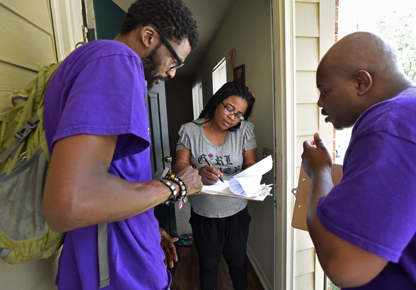 New Georgia Project volunteer Rodney King, left, and Corbin Spencer, the field director of the New Georgia Project, help Rueke Uyunwa register to vote in May 2017. HYOSUB SHIN / HSHIN@AJC.COM