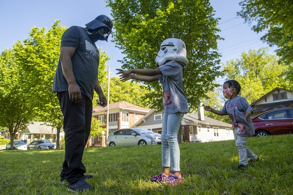 Parker Hughes (right) wants to join her father Todd and her older sister Laurel as they play in an open field following a pull-up portrait session with photographer Melissa Alexander in Atlanta’s West End community, Friday, May 1, 2020. The family has not been out much since the shelter-in-place order was placed on Georgia citizens. ALYSSA POINTER/ALYSSA.POINTER@AJC.COM