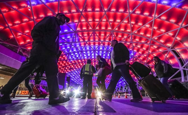 Under Super Bowl colors passengers travel under the illuminated canopy on the North Terminal at Hartsfield-Jackson International Airport that was bustling with passengers arriving for the Super Bowl Friday, Feb. 1, 2019 and airport officials are ramping up operations for even heavier traffic to come. JOHN SPINK/JSPINK@AJC.COM