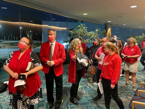 A loose coalition of disgruntled residents, wearing red clothing and masks, wait to enter the Board of Commissioner's Tuesday night meeting to express their opposition to a residential development in southeastern Gwinnett County. (Tyler Wilkins / tyler.wilkins@ajc.com)