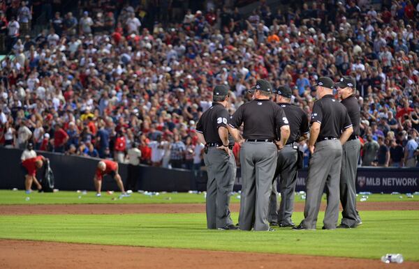 October 5, 2012 Atlanta - Umpires confer as Atlanta Braves ground crew members clean trash off the field after fans littered the area protesting an infield fly rule call on Andrelton Simmons in the eighth inning of the National League wild card game at Turner Field in Atlanta on Friday, October 5, 2012. HYOSUB SHIN / HSHIN@AJC.COM