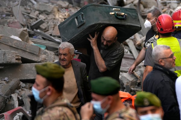 A man carries a suitcase as he leaves the site of an Israeli airstrike that hit central Beirut, Lebanon, Saturday, Nov. 23, 2024. (AP Photo/Hussein Malla)