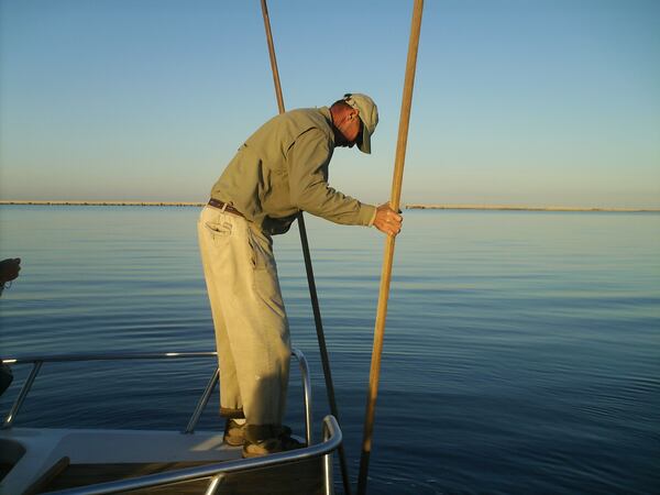 An oysterman works his oyster tongs in Apalachicola Bay near St. George Island. In the distance is the five-mile long bridge that connects the island to the mainland. Credit: Blake Guthrie