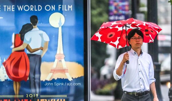 A man walks by a colorful advertisement at a MARTA bus stop at Peachtree Circle and Peachtree Street in Midtown on Thursday as thunderstorms made their way across North Georgia.