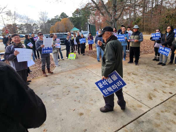 Korean Americans in Duluth hold signs that read, "Impeach Yoon Suk Yeol," and "We condemn the illegal martial law decree," Saturday following the National Assembly's vote to impeach South Korean President Yoon.