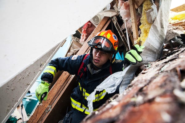 A rescue worker searches inside a mobile home Monday in Albany. (Credit: Branden Camp / Associated Press)