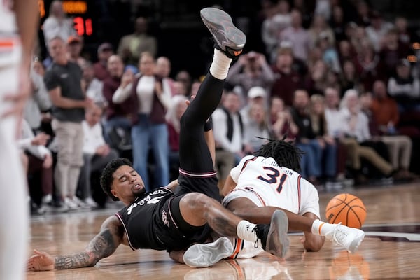 Texas A&M guard Jace Carter, left, and Auburn forward Chaney Johnson, right, dive for a loose ball near half court during the second half of an NCAA college basketball game Tuesday, March 4, 2025, in College Station, Texas. (AP Photo/Sam Craft)