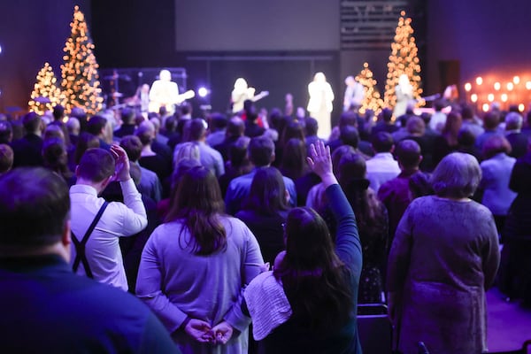 People raise their hands during song at the funeral for Erin Michelle West on Monday, Dec. 23, 2024 at DOXA Church in Fitchburg, Wis. (Owen Ziliak/Wisconsin State Journal via AP)