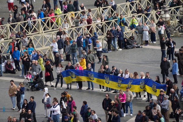 Faithful hold Ukrainian national flags as Cardinal Michael Czerny, prefect of the Dicastery for Promoting Integral Human Development, and delegate of Pope Francis celebrates a mass for the members of the world of volunteers in St. Peter's Square at The Vatican, Sunday, March 9, 2025. (AP Photo/Gregorio Borgia)