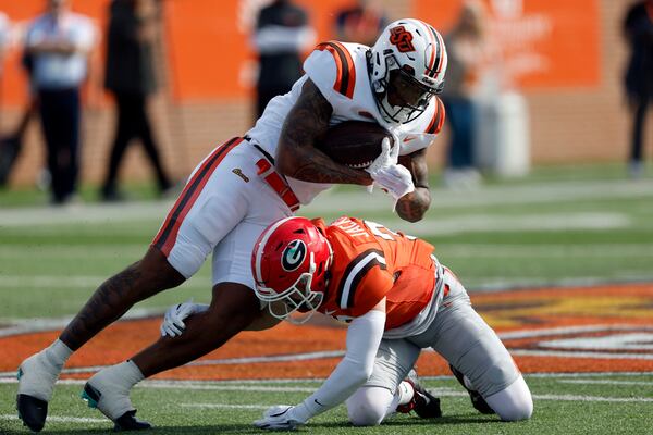 National team running back Ollie Gordon II, top, of Oklahoma State, is tackled by American team defensive back Dan Jackson, bottom, of Georgia, as he carries the ball during the first half of the Senior Bowl NCAA college football game, Saturday, Feb. 1, 2025, in Mobile, Ala. (AP Photo/Butch Dill)