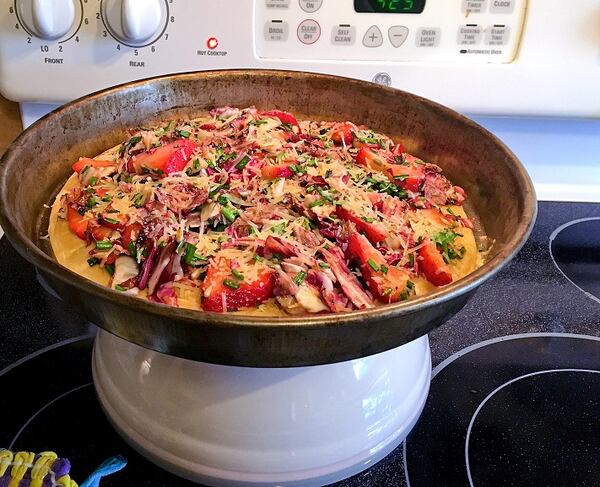 This pizza, shown in a metal baking pan, is Strawberries, Parmesan & Red Chicory Pizza. It is served on a ready-made pizza pie. (Karen Kane/ Pittsburgh Post-Gazette/TNS)