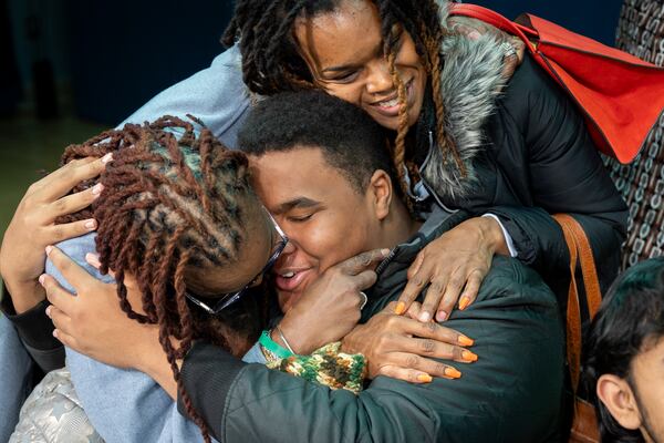 Jalen Smallwood, 17,  is hugged by his grandmother Sharon (left) and mother Nicole (top) after finding out he got admitted early to Georgia Tech at a ceremony at Benjamin E. Mays High School in Atlanta on Friday, December 6, 2024. (Arvin Temkar / AJC)