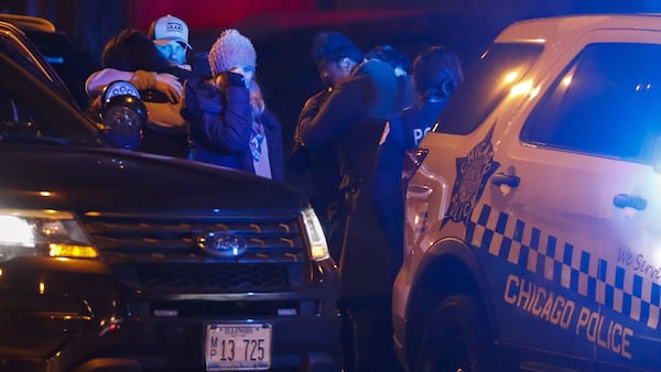 Mourners embrace as the procession  carrying the bodies of Chicago police officers Eduardo Marmolejo and Conrad Gary arrive at the medical examiner's office early Tuesday morning, Dec. 18, 2018. The officers were struck and killed Monday evening by a train as they investigated a shots-fired call on the city’s South Side.