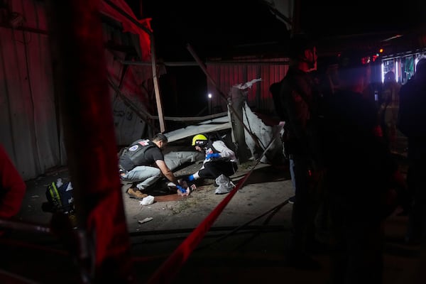 Members of ZAKA rescue services clean the blood stains at the site where a rocket fired from Lebanon hit a storage facility in the northern Israeli town of Nahariya, killing two people on Tuesday, Nov. 12, 2024. (AP Photo/Francisco Seco)