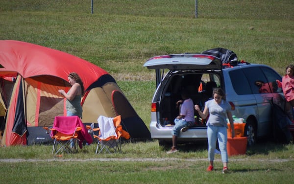 As her kids play nearby, Cassandra Hendon (left) checks her phone near her family's campsite near Atlanta Motor Speedway. The Hendon's left their Vero Beach home to escape Hurricane Irma. (MITCHELL NORTHAM/AJC)