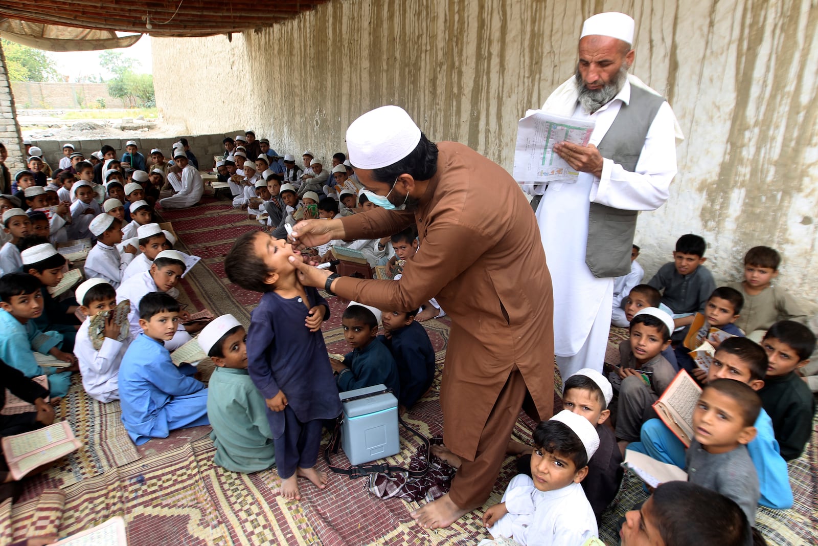 A health worker administers a polio vaccine to a boy at a local Madrassa, at a neighborhood of Jalalabad, east of Kabul, Afghanistan, Tuesday, Oct. 29, 2024. (AP Photo/Shafiullah Kakar)