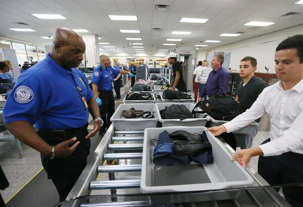 May 25, 2016 - Atlanta - TSA agent Darren Walker (left) helps passengers using the new system, where they slide their baggage onto the automated rollers. TSA unveiled new security "smart lanes" that have been installed in the South Security Checkpoint, which feature automated equipment that handles baggage. BOB ANDRES / BANDRES@AJC.COM