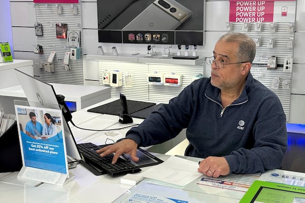 Nizam Abazid sits in his cellular shop in Dearborn, Mich., Tuesday, Dec. 10, 2024. Abazid, 59, left Syria in 1984. (AP Photo/Corey Williams)