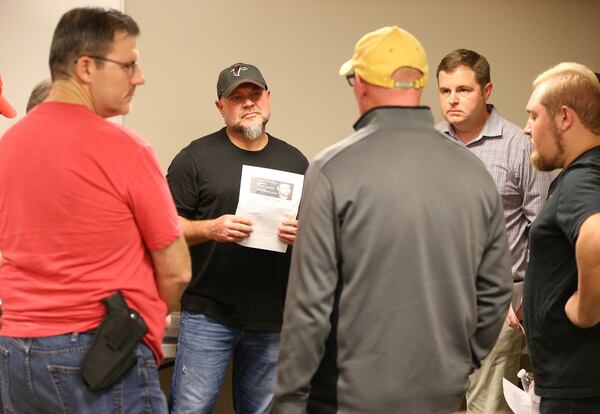 Beau Adams (second from left), pastor of Community Bible Church in Stockbridge, discusses the Bible lesson with a group of men during the church’s monthly men’s study group at the American Heritage Gun Range in McDonough. CURTIS COMPTON / CCOMPTON@AJC.COM