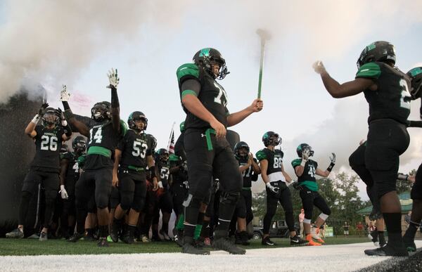 Roswell's Alek Nikolich carries a sledge hammer as the team comes out onto the field to take on Milton in their high school football game, Friday, Sept. 29, 2017, in Roswell. (John Amis/Special to the AJC)