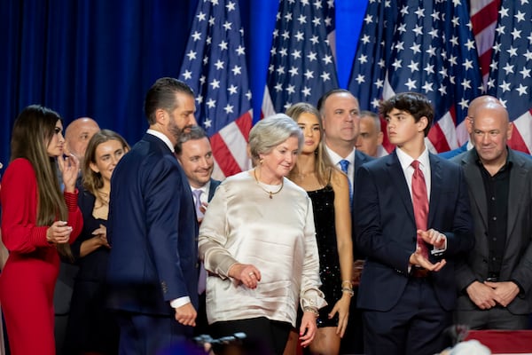 From left, Kimberly Guilfoyle, Tony Fabriozio, Donald Trump Jr., fourth from left, Justin Caporale, Susie Wiles, Kai Madison Trump, Dan Scavino, Corey Lewandowski, Donald Trump III and Dana White listen as Republican presidential nominee former President Donald Trump speaks at an election night watch party Wednesday, Nov. 6, 2024, in West Palm Beach, Fla. (AP Photo/Alex Brandon)