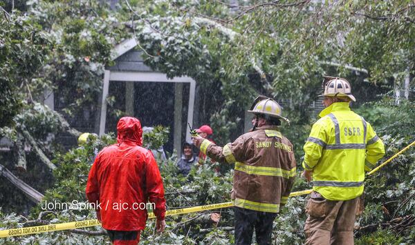 Outside of where a tree crashed into a home and killed a Sandy Springs man, authorities discuss how to get inside the home on Monday, Sept. 11, 2017. (JOHN SPINK/AJC)