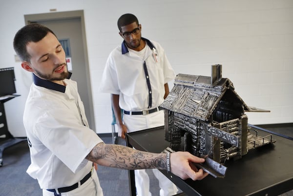 Gage Bryant (left) and Christopher Wilson in July show a model house built out of steel that they constructed in their welding class. They are prisoners at the Gwinnett County Comprehensive Correctional Complex in Lawrenceville, which offered them the opportunity to learn welding. Bob Andres / bandres@ajc.com