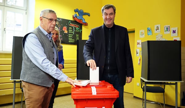 The governor of the German state of Bavaria and leader of the Christian Social Union (CSU), Markus Soeder, right, casts his vote at a polling station in Nuremberg, Germany, Sunday, Feb. 23, 2025, during the national election. (Daniel Karmann/dpa via AP)