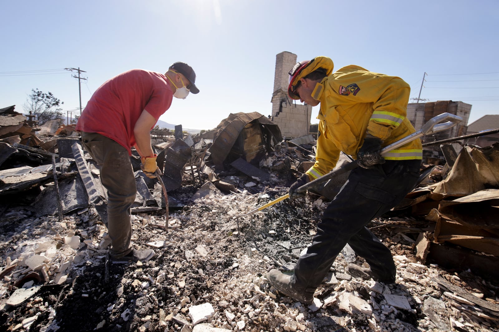 Todd Howard, left, sifts through the remains of his parents' fire-ravaged property with the help of firefighters after the Mountain Fire swept through, Thursday, Nov. 7, 2024, in Camarillo, Calif. (AP Photo/Ethan Swope)