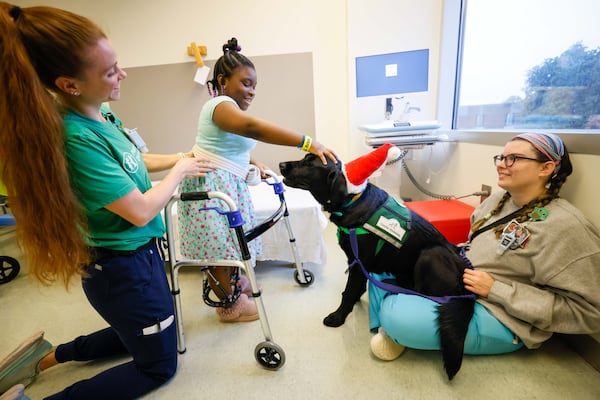 Emily Owie (11) smiles as she pets Conway, the new facility dog, at the Children’s Healthcare of Atlanta’s Scottish Rite; Haley Grayson, the Therapeutic Recreational Specialist, holds Conway. Tori Ragsdale, the Occupational Therapist, offers support from her back on Monday, Dec. 9, 2024.
(Miguel Martinez / AJC)