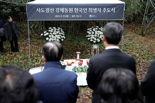 Relatives of Korean victims and South Korean officials offer a prayer during a memorial service at the site of former Fourth Souai Dormitory for the mine workers from the Korean Peninsula, in Sado, Niigata prefecture, Japan, Monday, Nov. 25, 2024, a day after boycotting a memorial organized by Japanese officials. The black banner reads "A memorial service for Korean forced laborer victims at Sado Mine." (AP Photo/Eugene Hoshiko)