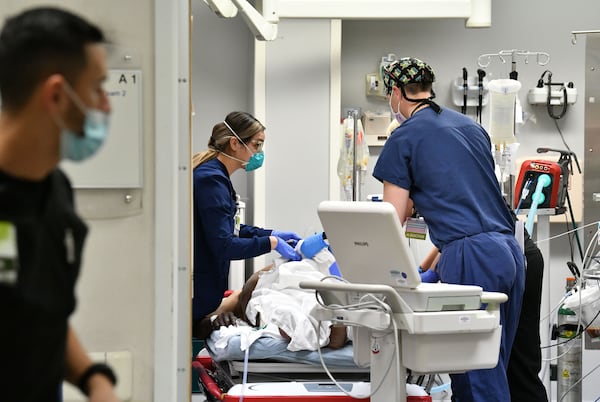 Medical staff treat a patient in a trauma room in the Emergency and Trauma Center at Northeast Georgia Medical Center in Gainesville on Wednesday. Hospitals are more full than they ever have been. Fatigue set in long ago. Most never imagined their hospitals could treat this many patients. (Hyosub Shin / Hyosub.Shin@ajc.com)