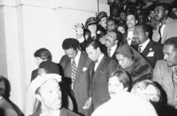 Democratic presidential hopeful Jesse Jackson, left, Louis Farrakhan, center, head of the Nation of Islam, and his wife, Betsy Farrakhan, bow their heads as the Rev. Clay Evans, behind Farrakhan, leads a prayer at Chicago’s City Hall on Feb. 9, 1984, Chicago, Ill. Jackson accompanied the religious leader as he registered to vote for the first time in his life.