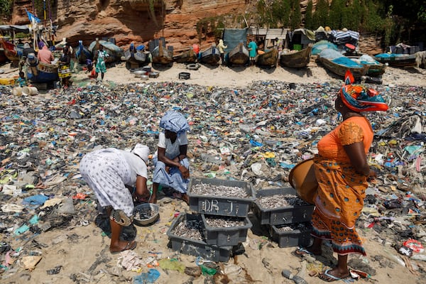 Women sort fish through textile waste on the beach shore at Jamestown in Accra, Ghana, Saturday, Oct. 19, 2024. (AP Photo/Misper Apawu)