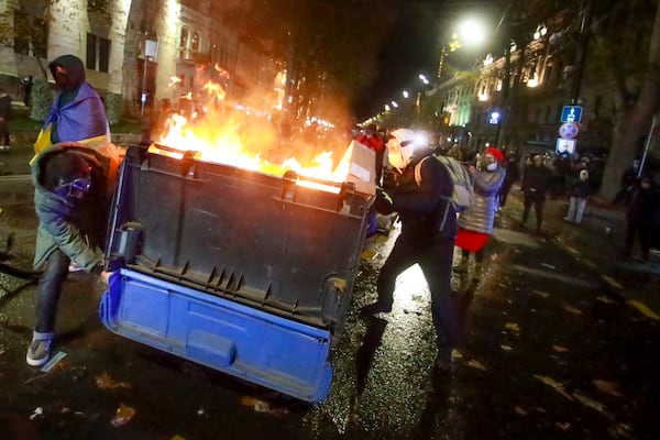 A group of protesters move a burning garbage container pouring into the streets following Georgian Prime Minister Irakli Kobakhidze's announcement, rallying outside the parliament building in Tbilisi, Georgia, on Friday, Nov. 29, 2024. (AP Photo/Zurab Tsertsvadze)