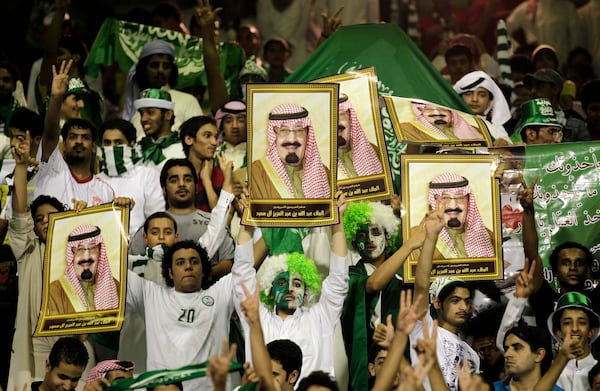 FILE - Saudi Arabia fans cheer as they hold pictures of King Abdullah of Saudi Arabia before their 2014 FIFA World Cup Asia qualifying soccer match against Australia at the Prince Muhammad bin Fahd Stadium in the eastern port city of Dammam, Saudi Arabia, Tuesday, Sept. 6, 2011. (AP Photo/Hassan Ammar, File)