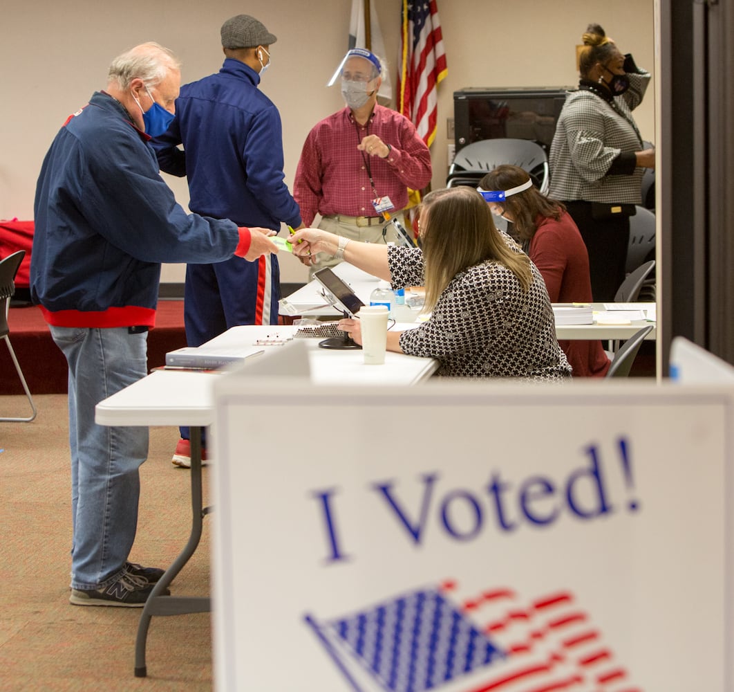 A poll worker hands a voter his card at the Dunwoody Library as the polls opened at 7am on election day Nov 3rd, 2020. PHIL SKINNER FOR THE ATANTA JOURNAL-CONSTITUTION