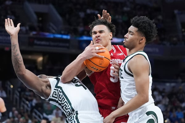 Wisconsin guard John Tonje (9) drives on Michigan State forward Coen Carr, left, and Michigan State guard Jaden Akins, right, during the second half of an NCAA college basketball game in the semifinals of the Big Ten Conference tournament in Indianapolis, Saturday, March 15, 2025. (AP Photo/Michael Conroy)