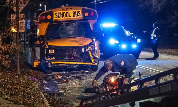 Workers inspect a motorcycle after it collided with a school bus early Thursday morning.