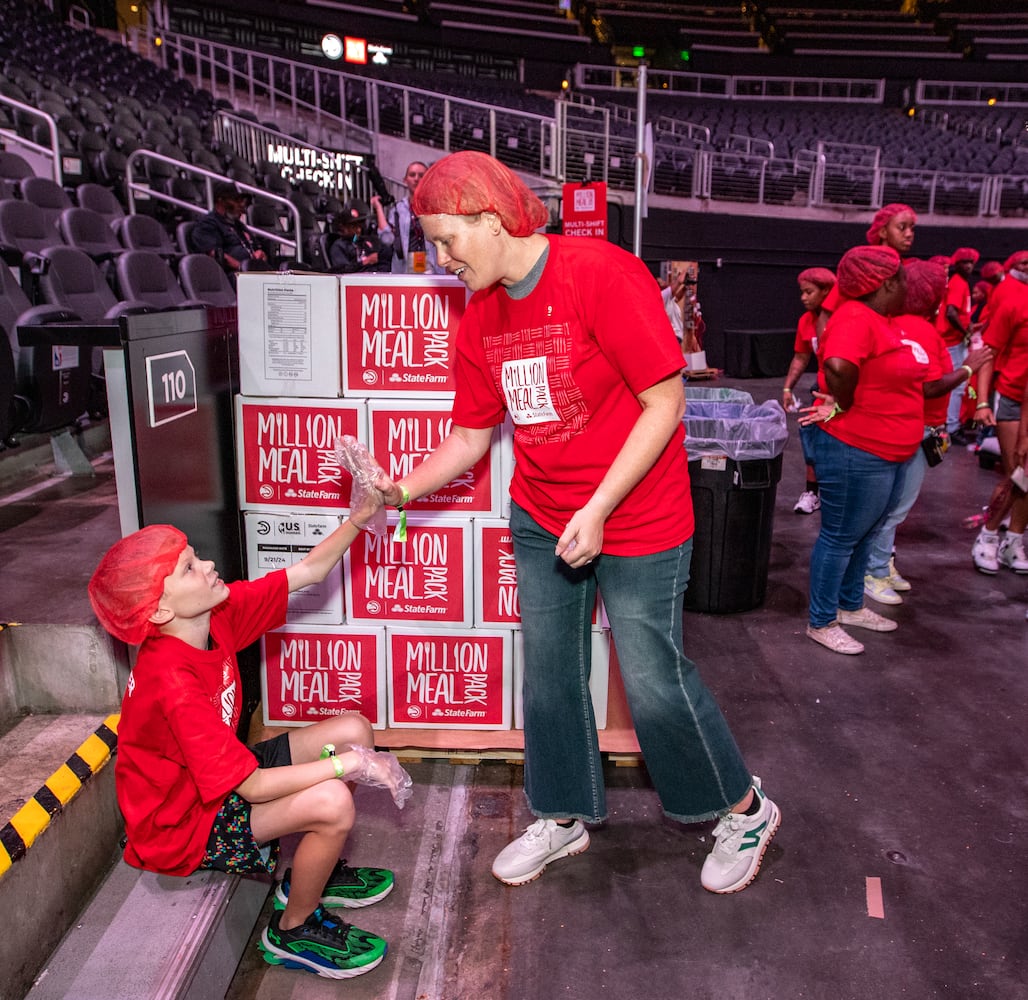 Russell Savage, 9, left, gets props from his mom Lacy Savage after completing the 1 1/2-hour packing of red lentil jambalaya kits for local food banks.   (Jenni Girtman for The Atlanta Journal-Constitution)