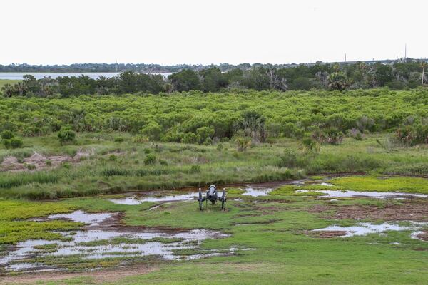 A cannon sits surrounded by puddles on a soggy field outside the walls of Fort Pulaski.