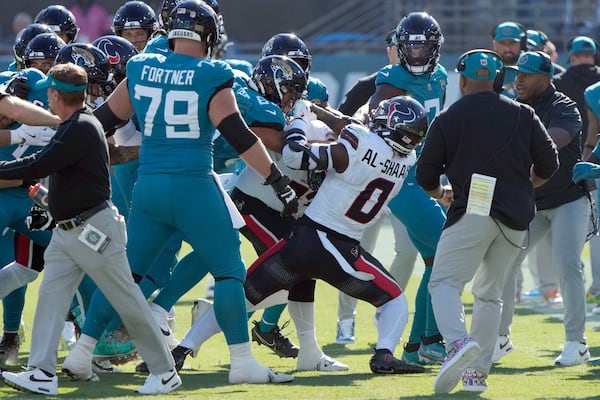 Players fight after Houston Texans linebacker Azeez Al-Shaair (0) hit Jacksonville Jaguars quarterback Trevor Lawrence with a late hit during the first half of an NFL football game Sunday, Dec. 1, 2024, in Jacksonville, Fla. (AP Photo/John Raoux)