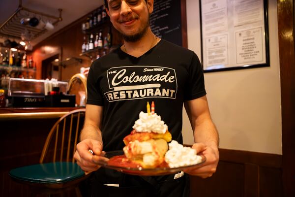 A server at the Colonnade delivers a towering plate of strawberry shortcake.