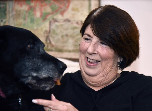 Toni Appling gives her dog Miss Maeve, an older and easygoing black Lab, a treat at her home in Johns Creek. As a co-founder of the Atlanta Dog Squad, she has helped rescue, foster and ultimately find homes for abandoned, neglected and sometimes abused Labrador retrievers and Lab mixes in Georgia. HYOSUB SHIN / HYOSUB.SHIN@AJC.COM